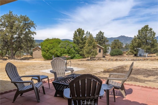 view of patio with a storage shed, a mountain view, and a fire pit