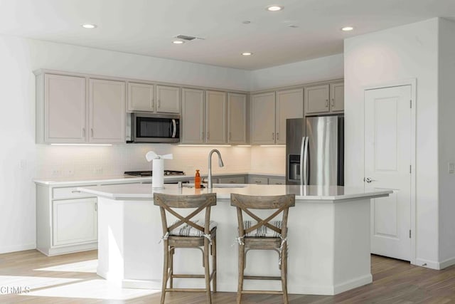 kitchen featuring light hardwood / wood-style flooring, sink, a center island with sink, and appliances with stainless steel finishes