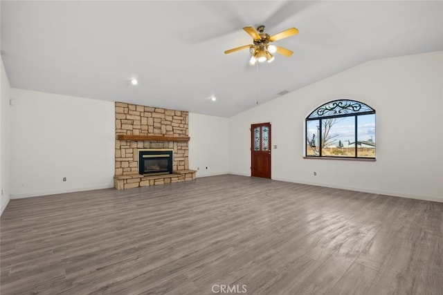 unfurnished living room featuring a stone fireplace, wood-type flooring, ceiling fan, and vaulted ceiling