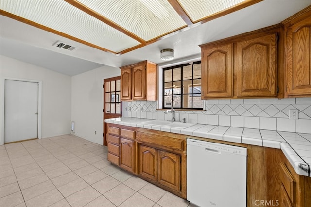 kitchen featuring light tile patterned flooring, tasteful backsplash, sink, tile counters, and white dishwasher