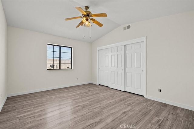 unfurnished bedroom featuring ceiling fan, lofted ceiling, light hardwood / wood-style floors, and a closet