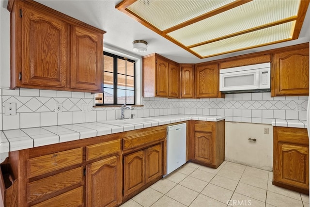 kitchen featuring light tile patterned flooring, tasteful backsplash, sink, tile counters, and white appliances