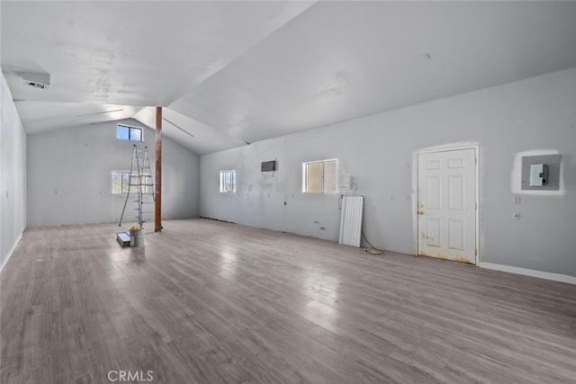 unfurnished living room featuring lofted ceiling, radiator, light hardwood / wood-style flooring, and electric panel