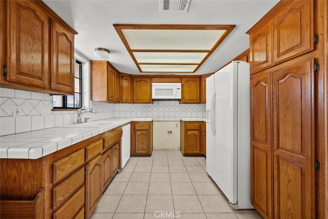 kitchen featuring tile countertops, sink, backsplash, light tile patterned floors, and white appliances