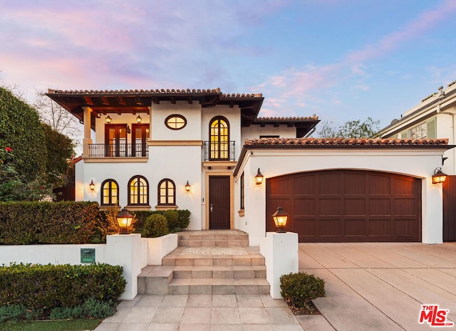 mediterranean / spanish home featuring a garage and a balcony