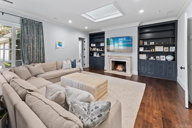 living room with dark wood-type flooring, built in features, a skylight, a fireplace, and ornamental molding