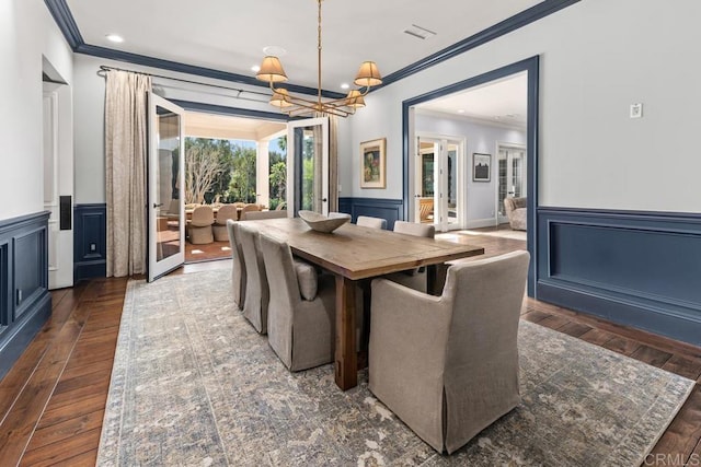 dining room with crown molding, a wainscoted wall, hardwood / wood-style floors, and a chandelier