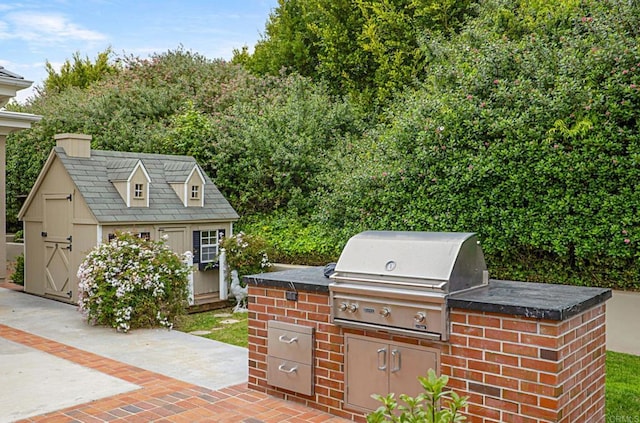 view of patio featuring exterior kitchen, grilling area, a storage shed, and an outbuilding