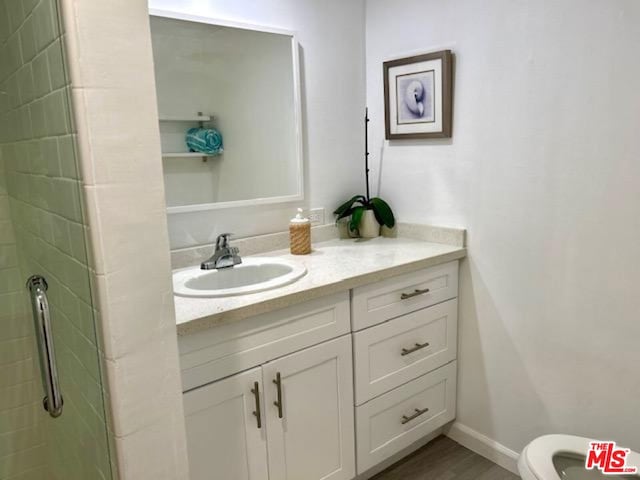 bathroom with walk in shower, vanity, and toilet