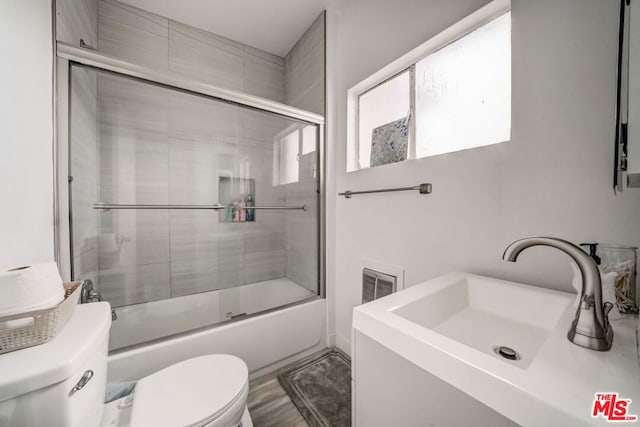 full bathroom featuring toilet, sink, and combined bath / shower with glass door