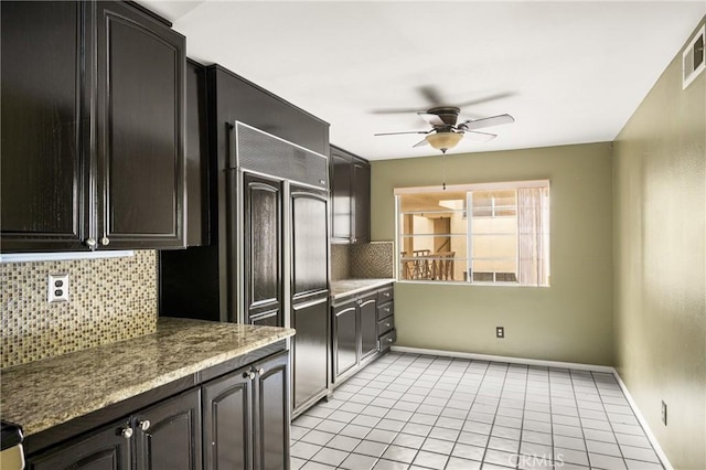 kitchen with light tile patterned flooring, light stone counters, backsplash, and ceiling fan