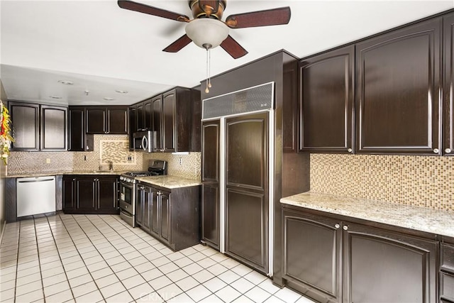 kitchen featuring appliances with stainless steel finishes, dark brown cabinets, backsplash, and light stone counters