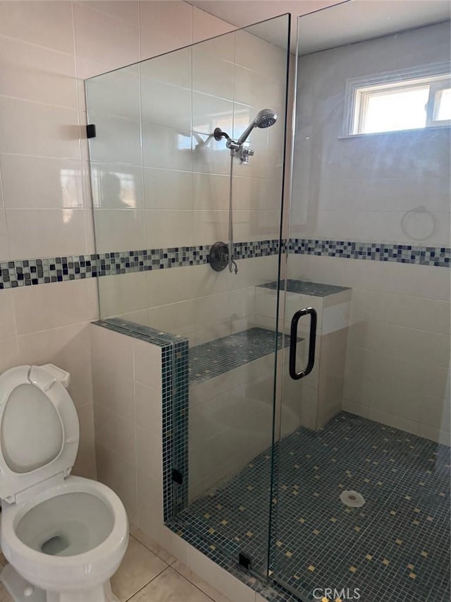 bathroom with a shower with door, tile patterned floors, and toilet