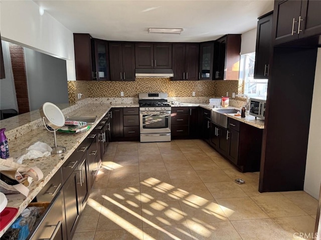 kitchen featuring light tile patterned flooring, sink, dark brown cabinets, stainless steel appliances, and decorative backsplash