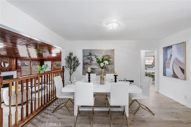 dining room featuring a fireplace, baseboards, and wood finished floors