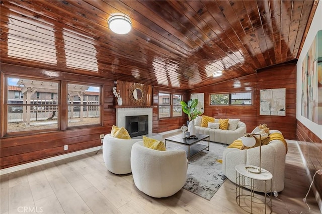 living room featuring lofted ceiling, wood walls, a fireplace, wood finished floors, and wood ceiling