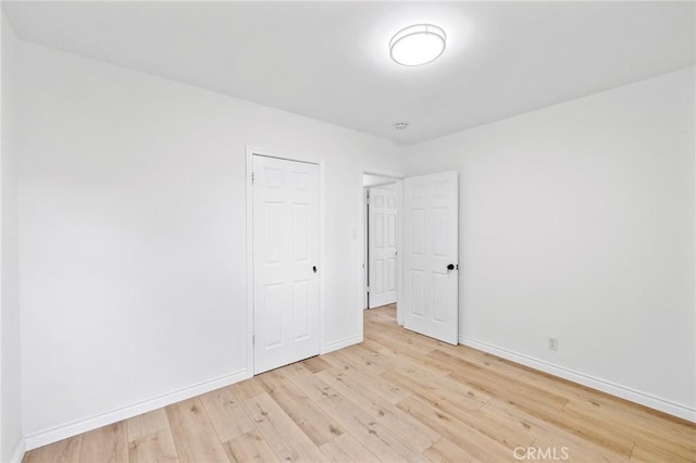 unfurnished bedroom with light wood-style flooring and baseboards