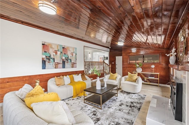 living room featuring wooden ceiling, wood walls, and a fireplace with raised hearth