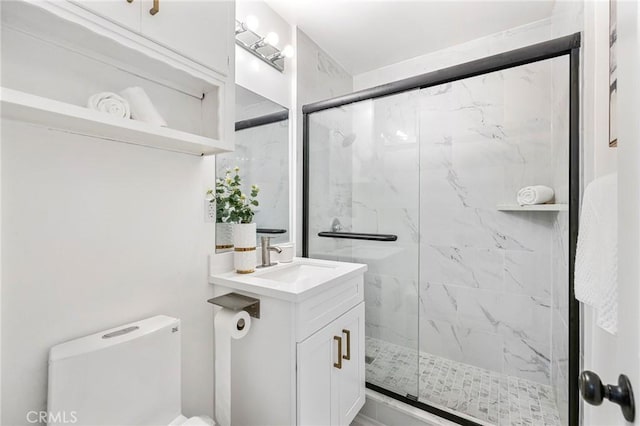 bathroom with toilet, a marble finish shower, and vanity