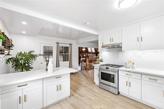 kitchen with light countertops, decorative backsplash, gas range, light wood-type flooring, and under cabinet range hood