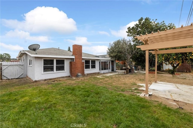 rear view of property featuring a lawn, stucco siding, fence, and a pergola