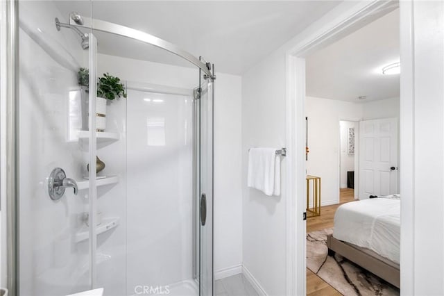 bathroom featuring wood finished floors, a shower stall, and baseboards