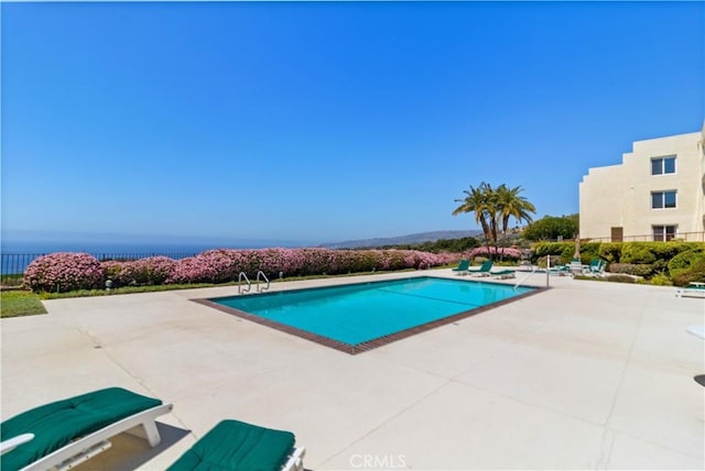 view of swimming pool with a water view and a patio area