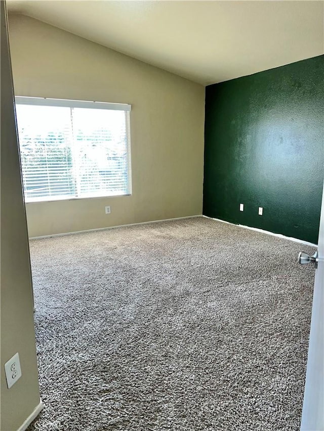 carpeted spare room featuring vaulted ceiling