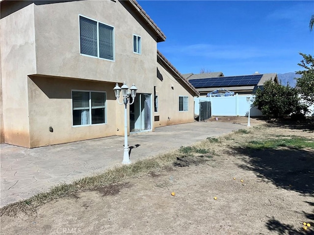 back of property with a patio and solar panels