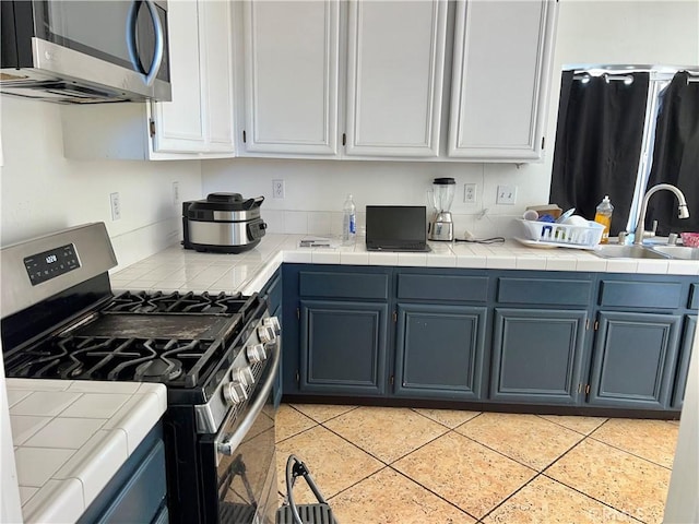 kitchen featuring sink, stainless steel appliances, white cabinets, and blue cabinetry