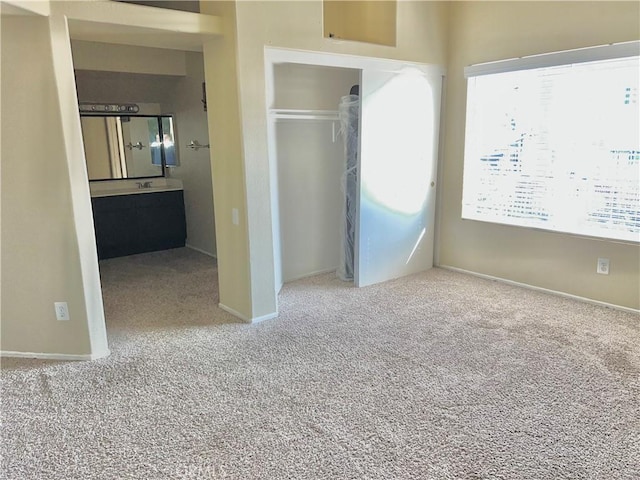 unfurnished bedroom with ensuite bathroom, a closet, and carpet