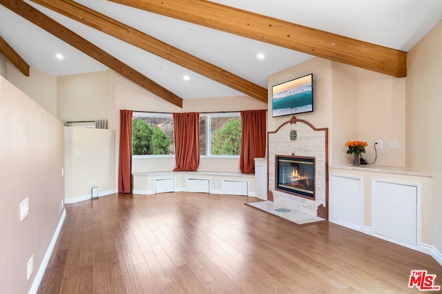 unfurnished living room featuring a brick fireplace, vaulted ceiling with beams, and light wood-type flooring