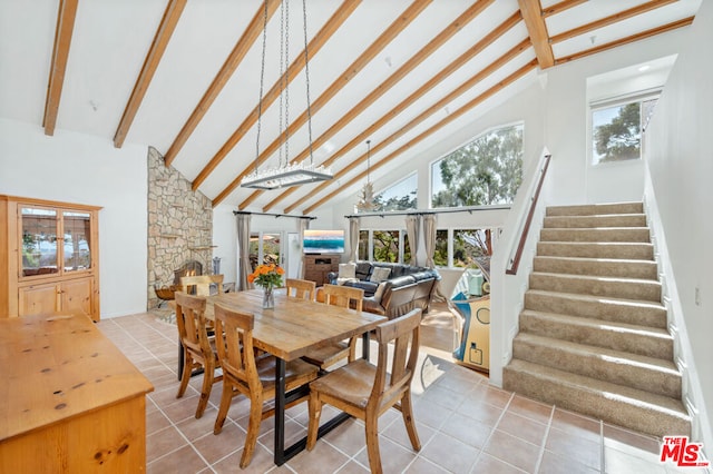 tiled dining area featuring a stone fireplace, high vaulted ceiling, and beamed ceiling