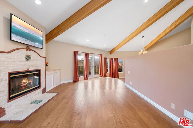 unfurnished living room with light hardwood / wood-style flooring, a notable chandelier, a fireplace, and beamed ceiling