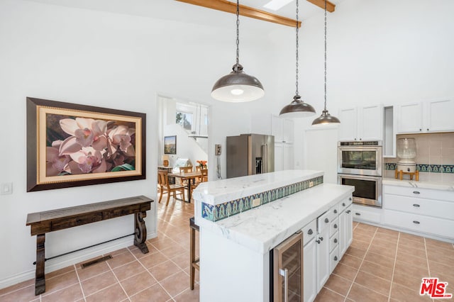 kitchen with white cabinetry, appliances with stainless steel finishes, high vaulted ceiling, and decorative light fixtures