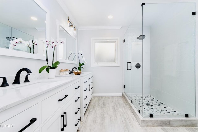 bathroom with ornamental molding, wood-type flooring, vanity, and a shower with shower door