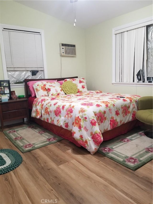 bedroom featuring a wall unit AC and wood finished floors