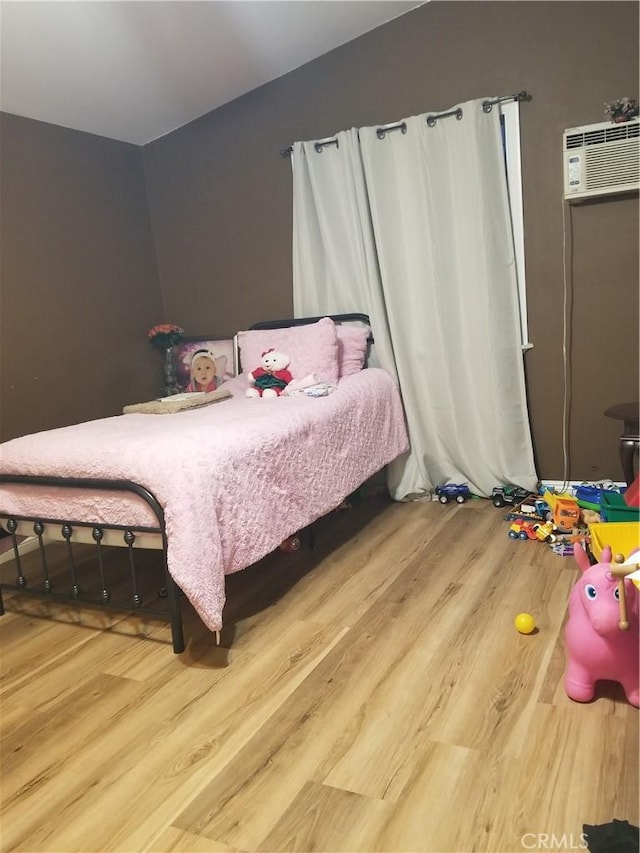 bedroom with lofted ceiling, an AC wall unit, and wood finished floors