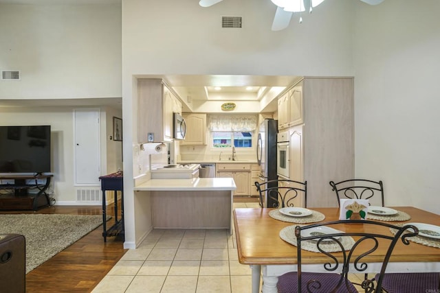 kitchen with light brown cabinetry, sink, light tile patterned floors, appliances with stainless steel finishes, and kitchen peninsula