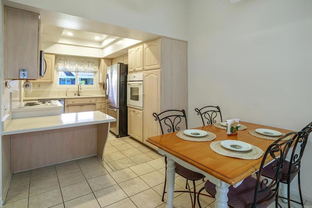 kitchen featuring appliances with stainless steel finishes, light brown cabinetry, sink, and light tile patterned floors