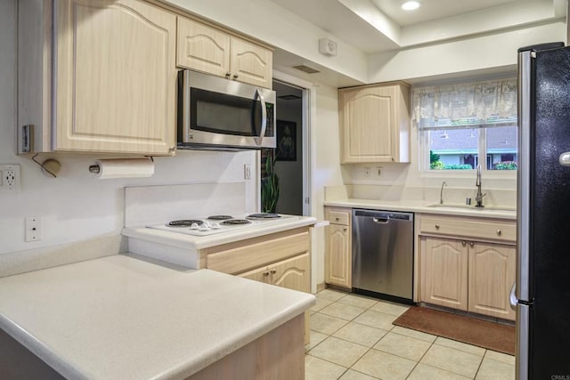 kitchen with light brown cabinetry, appliances with stainless steel finishes, and a sink