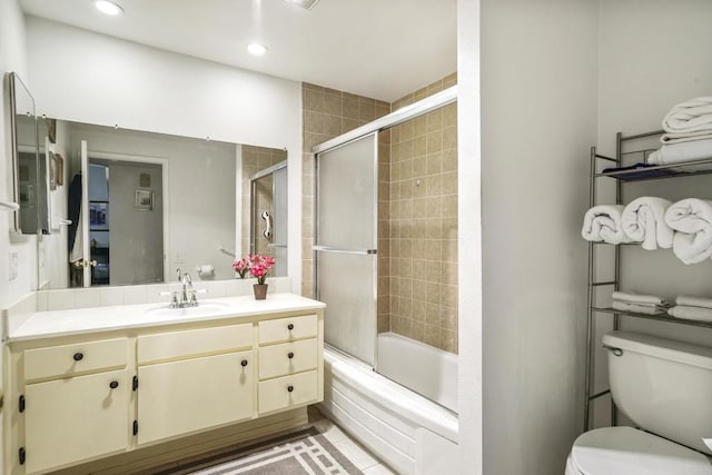 bathroom with recessed lighting, combined bath / shower with glass door, vanity, and toilet