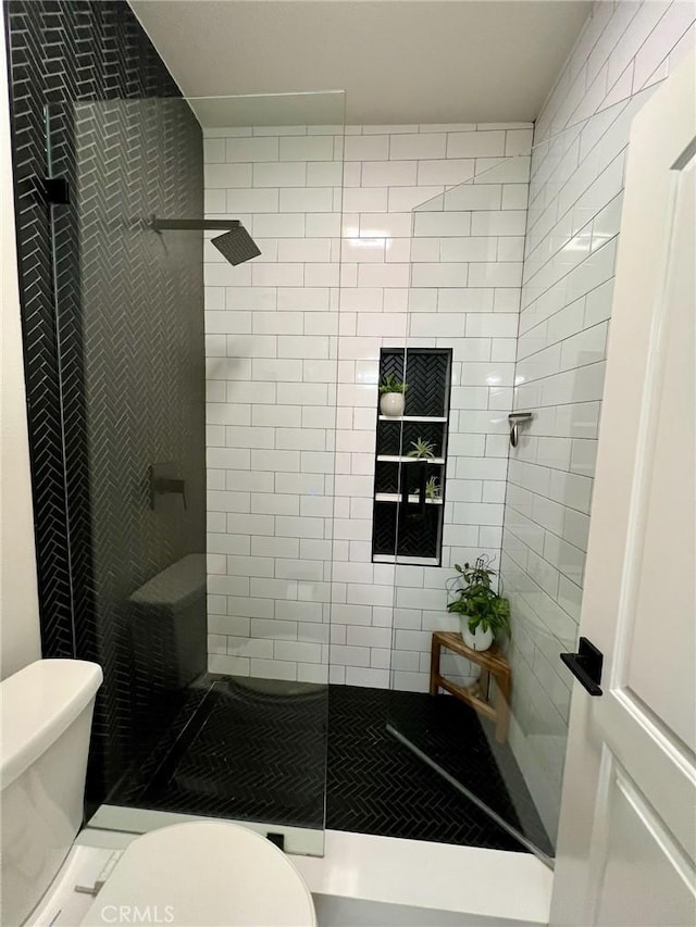 bathroom with a tile shower and toilet