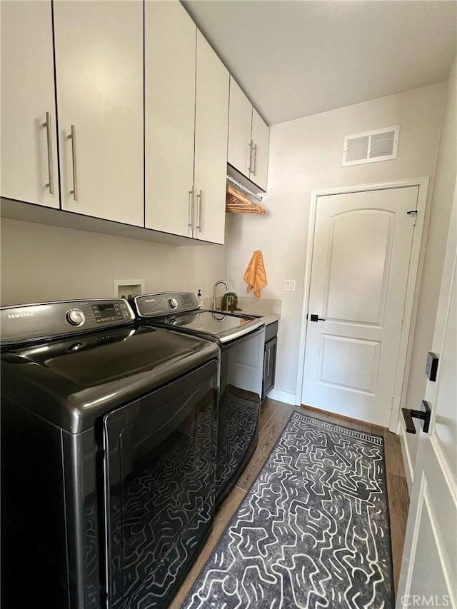 washroom featuring cabinets, sink, dark hardwood / wood-style flooring, and washing machine and dryer