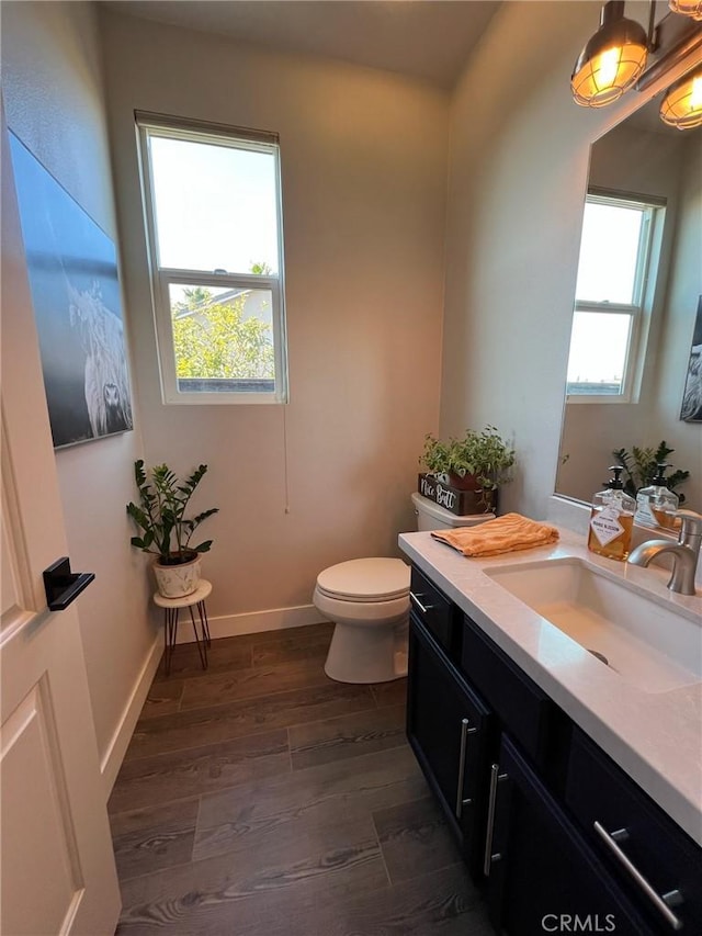 bathroom with wood-type flooring, a healthy amount of sunlight, vanity, and toilet