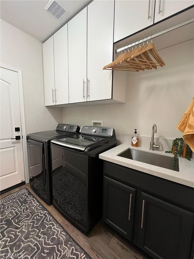 laundry room with sink, hardwood / wood-style flooring, cabinets, and washing machine and clothes dryer