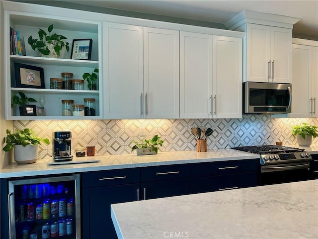 kitchen with wine cooler, blue cabinetry, white cabinetry, stainless steel appliances, and backsplash