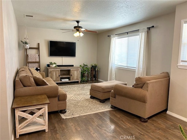 living room featuring ceiling fan, a textured ceiling, and dark hardwood / wood-style flooring