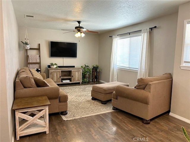 living area featuring visible vents, a ceiling fan, a textured ceiling, wood finished floors, and baseboards