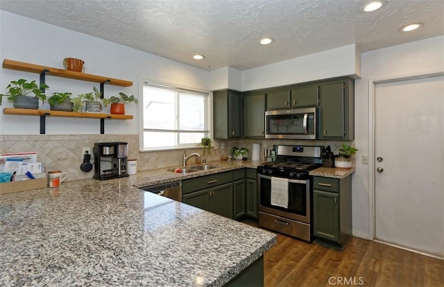 kitchen featuring stainless steel appliances, light stone countertops, sink, and green cabinetry